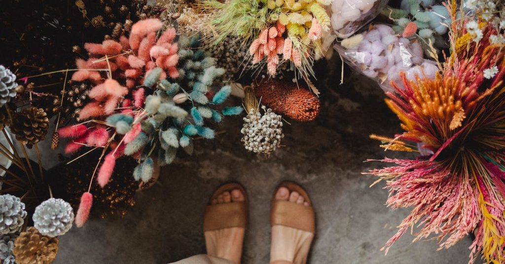 crop-faceless-woman-standing-near-bright-flowers-in-floral-market