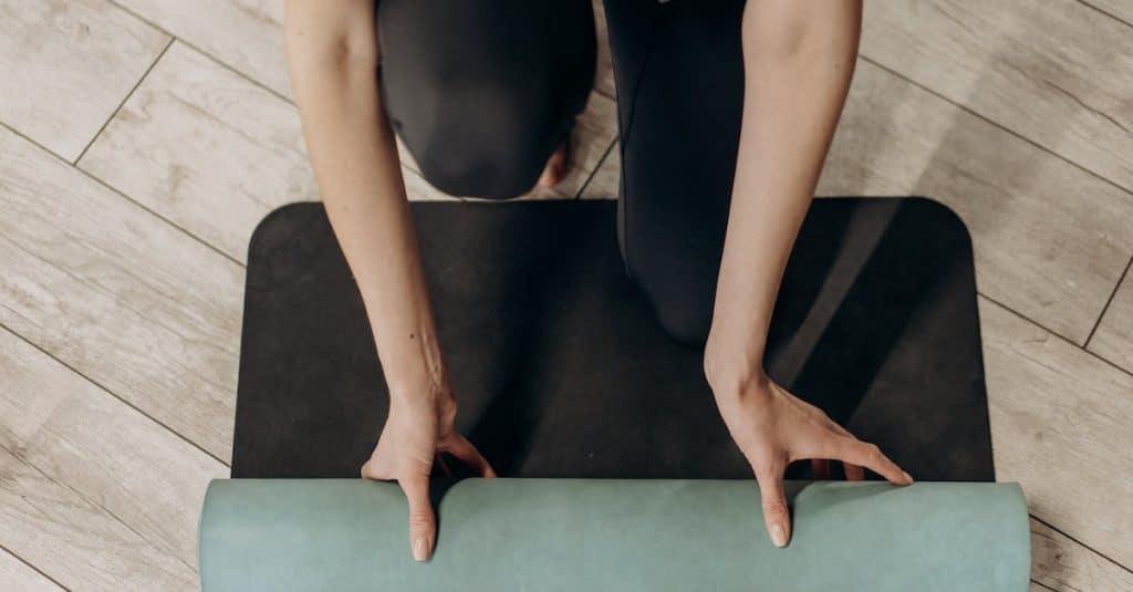 woman-in-black-leggings-unrolling-a-yoga-mat