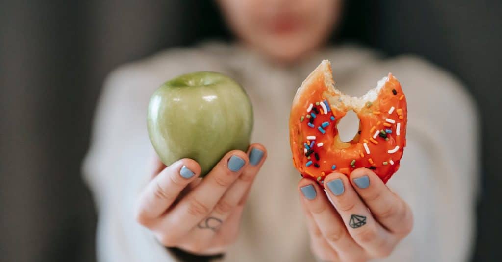 woman-showing-apple-and-bitten-doughnut